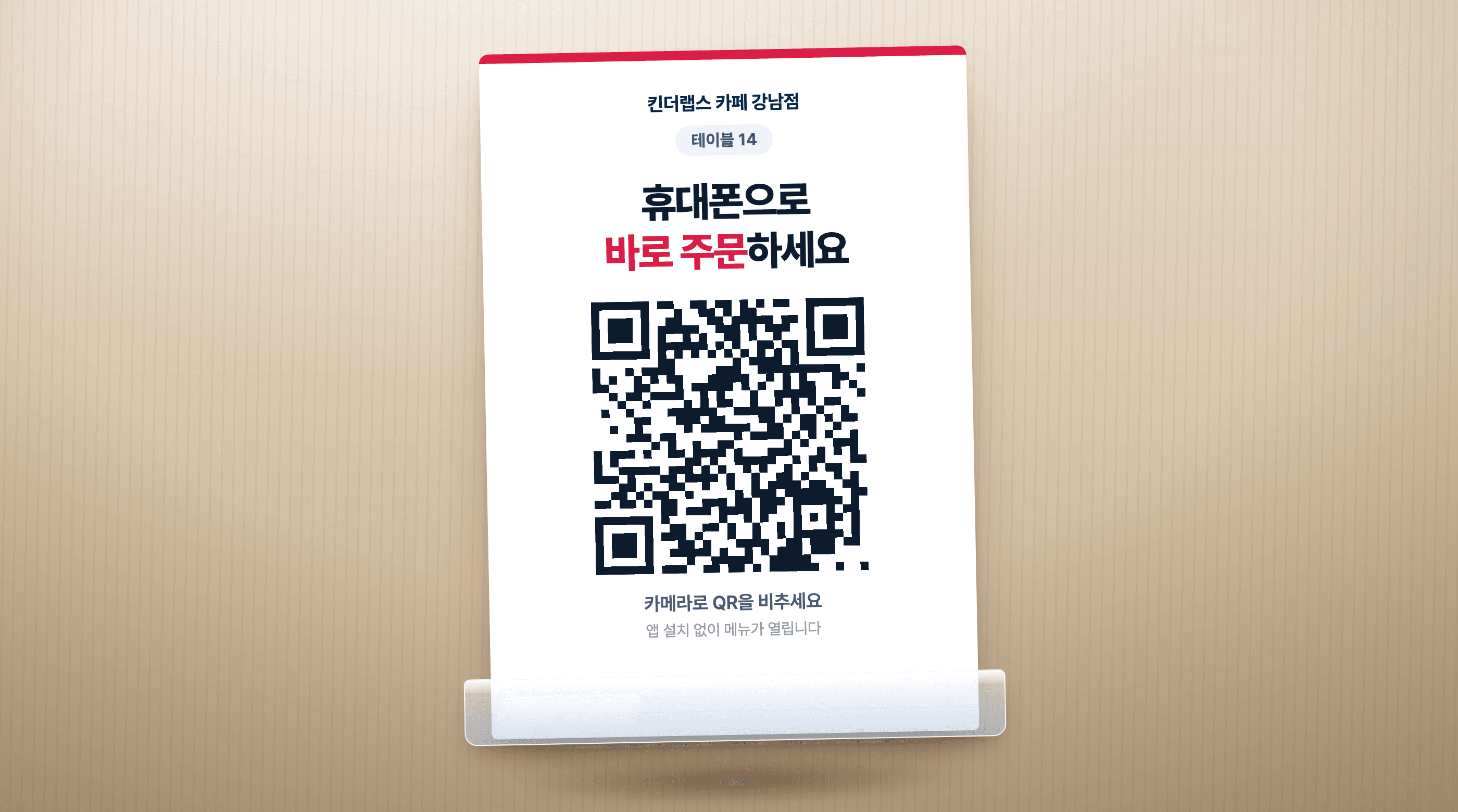 테이블에 놓인 QR 안내 스탠드 — 매장명과 테이블 번호, '휴대폰으로 바로 주문하세요' 문구와 QR 코드